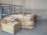 a large pile of wood in a warehouse with pallets of wood
