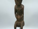 une image représentant une statue d'une personne assise sur un socle en bois