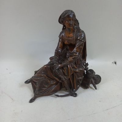 une statue en bronze représentant une femme assise sur un banc