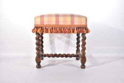 un petit tabouret dont l'assise est rembourrée et à carreaux