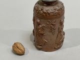 a small jar with a lid and a nut on the ground
