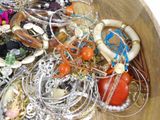 a wooden bowl filled with assorted jewelry and bracelets