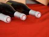 four bottles of wine are lined up on a red table cloth
