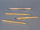 Plusieurs stylos sont alignés les uns à côté des autres sur une table.