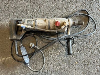une perceuse posée par terre à côté de quelques fils électriques