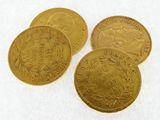four gold coins are sitting on top of a white surface