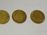 three gold coins sitting next to each other on a white surface