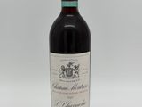 a bottle of red wine sitting on top of a white table