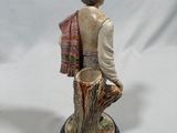 figurine of a man with a hat and scarf on a tree stump