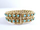 a close up of a gold bracelet with turquoise beads on it