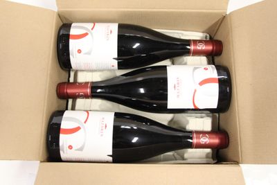 three bottles of wine in a cardboard box on a table