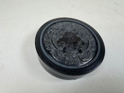 une image représentant un récipient noir posé sur une surface blanche