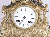 a gold clock with a white face and black hands