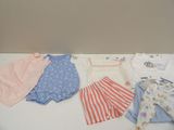 Plusieurs vêtements pour bébé sont disposés sur une table blanche