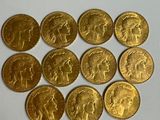 six types différents de pièces d'or sont disposés sur une surface blanche