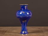 un vase bleu orné d'étoiles dorées, posé sur une table en bois