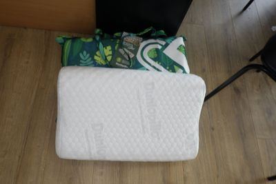 un oreiller blanc posé par terre à côté d'une chaise noire