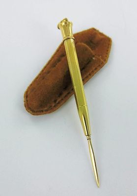 a gold pen and a leather case on a white surface