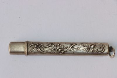 un vieux tube métallique argenté orné d'un motif floral