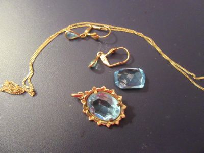 un collier en or orné d'une pierre bleue et d'un pendentif représentant un oiseau