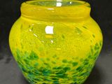 un vase jaune et vert posé sur une surface noire
