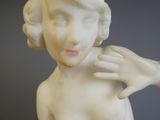 une statue représentant une femme les mains jointes sur la poitrine