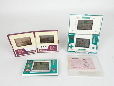 three electronic game consoles sitting next to each other on a table