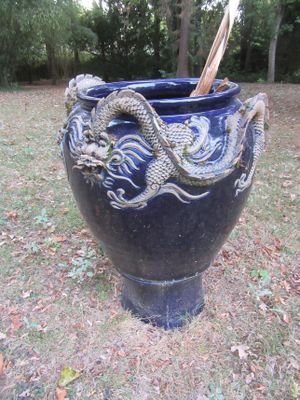un vase bleu orné d'un dragon, posé dans l'herbe