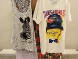 Deux t-shirts et une jupe sont exposés devant une boîte en carton