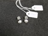 une paire de boucles d'oreilles en perles et une étiquette de prix posée sur une surface noire