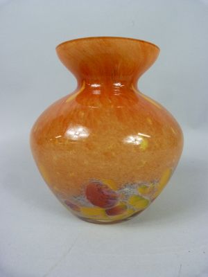 un vase orange posé sur une surface blanche