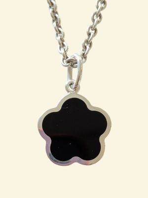 un gros plan d'un pendentif en forme de fleur noire monté sur une chaîne en argent