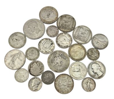 a pile of old silver coins on a white surface