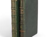 two green books sitting on top of each other on a white surface