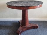 une petite table avec un plateau en marbre posée sur un sol recouvert de moquette