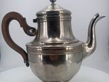 silver plated teapot with wooden handle on a white table