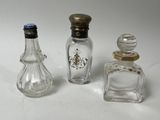 trois petites bouteilles en verre et une petite bouteille en verre posées sur une surface blanche