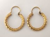 une paire de boucles d'oreilles en or sur fond blanc