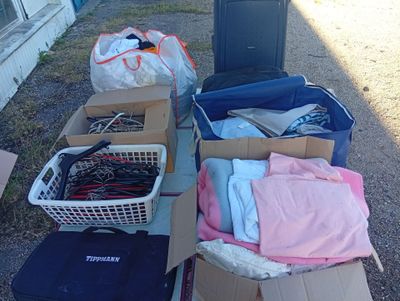 de nombreux cartons contenant des vêtements et d'autres objets, posés par terre
