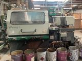 Plusieurs seaux de peinture sont alignés à côté d'une machine dans une usine