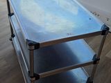une table en métal avec un plateau en verre posée sur un parquet en bois massif