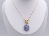 a gold plated necklace with a blue stone pendant on a mannequin