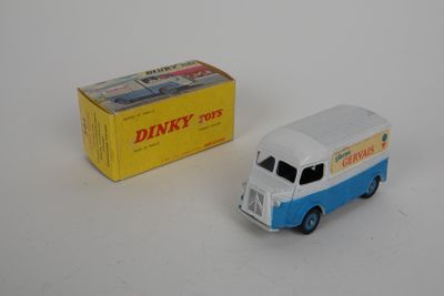 une petite camionnette miniature à côté d'une boîte posée sur une surface blanche