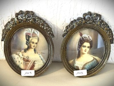 Deux portraits encadrés, représentant une femme et un homme, sont exposés