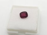 a close up of a red garnet stone on a white surface