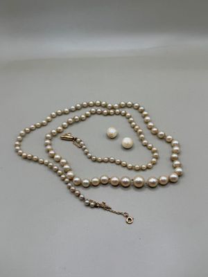 un gros plan d'un collier et de boucles d'oreilles en perles blanches posés sur une surface blanche