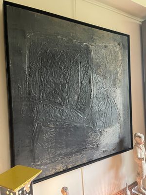 a painting on the wall next to a table with a lamp