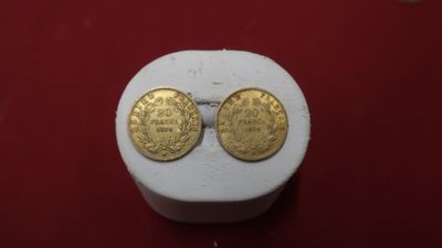 two gold coins sitting on top of a white box