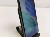 an image of a black phone on a stand on a white surface
