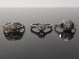 trois bagues en argent serties de diamants sur un fond noir